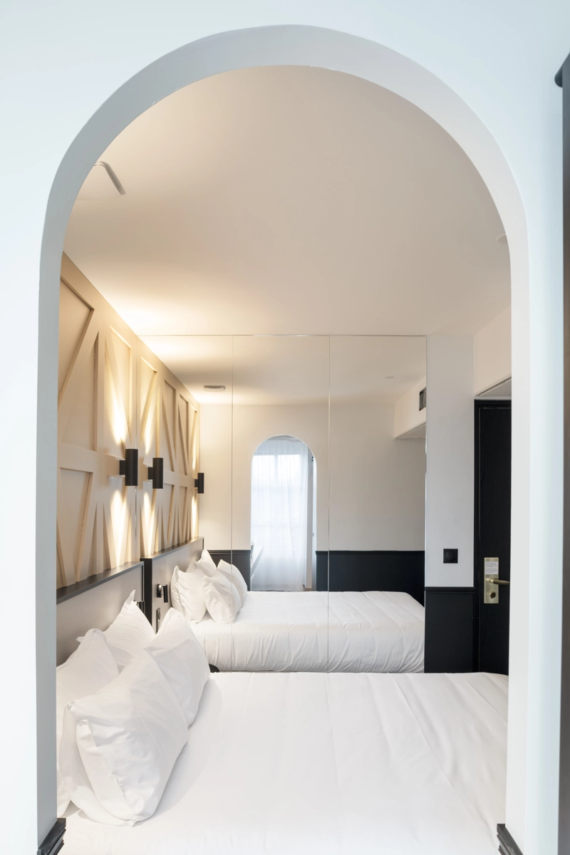 Hotel_Darcy40 Homme d’affaires en costume qui se détend sur le lit d'une chambre d'hôtel avec son ordinateur portable et un dossier, idéal pour une soirée étape solo.